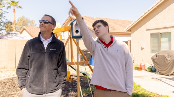 Photo of student Cartner Snee and professor Kevin McGraw standing in a backyard