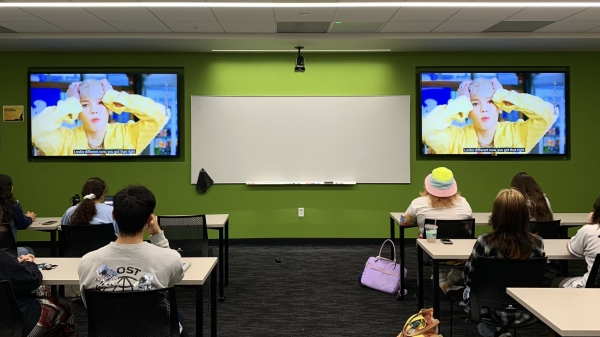 Students seated in a classroom watching K-pop videos.