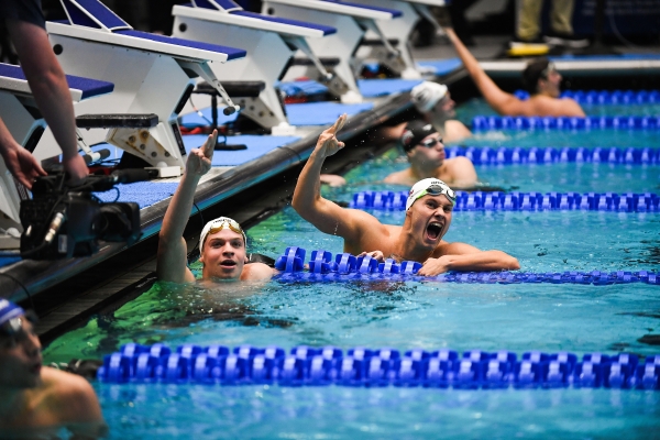Male swimmers cheer in lanes in a pool