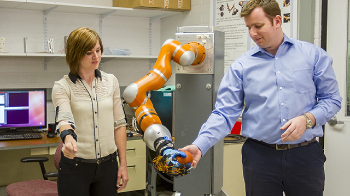 two people interacting with robotic arm