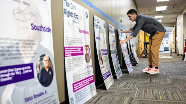 Person working to mount poster boards on wall that are lined up on floor